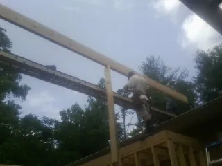 Carpenter setting a ridge beam over a new addition frame — Ice Dam Removal by Roofing Brothers in Brevard