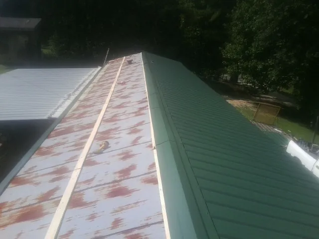Old rusted panels beside newly installed green metal roofing — Wind Damage Roof Repair by Roofing Brothers in Brevard